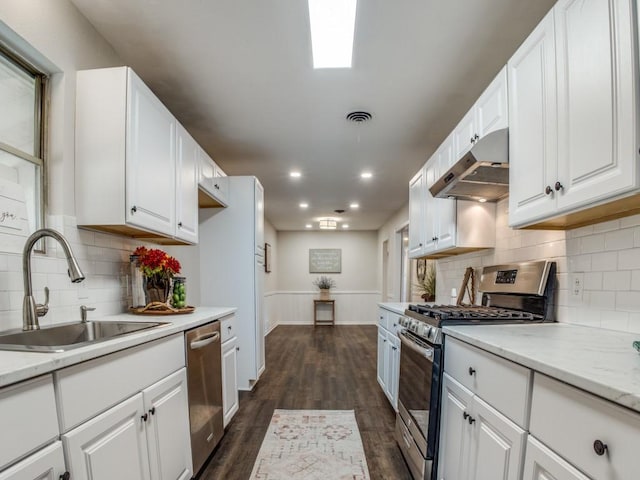 kitchen featuring under cabinet range hood, a sink, visible vents, white cabinets, and appliances with stainless steel finishes