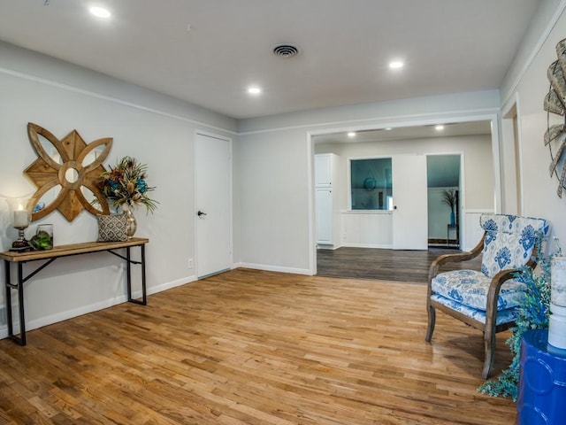 living area with baseboards, wood finished floors, visible vents, and recessed lighting