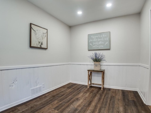 spare room with dark wood-style floors, recessed lighting, a wainscoted wall, and visible vents