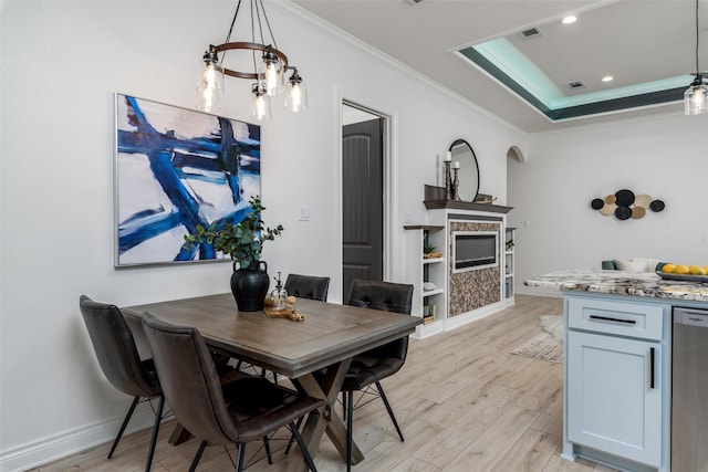 dining area with light wood-style floors, visible vents, a fireplace, and ornamental molding