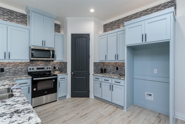 kitchen featuring crown molding, stainless steel appliances, tasteful backsplash, light wood-style floors, and light stone countertops