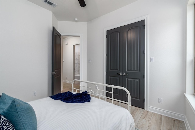 bedroom featuring light wood-style floors, baseboards, visible vents, and a closet