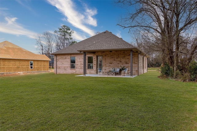 rear view of house with a patio area, roof with shingles, a lawn, and brick siding