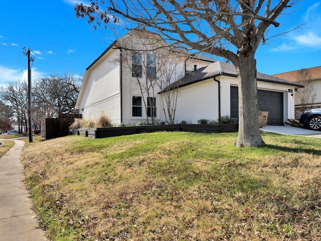 view of side of property featuring a garage, brick siding, concrete driveway, and a yard