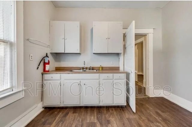 kitchen featuring baseboards, dark wood-style flooring, white cabinets, and a sink