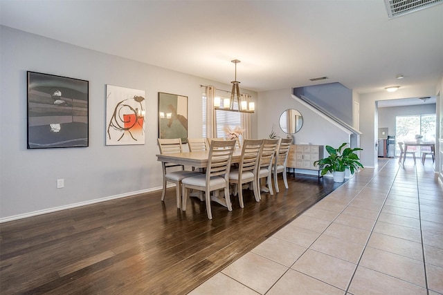 dining area with light wood-type flooring, visible vents, baseboards, and a chandelier