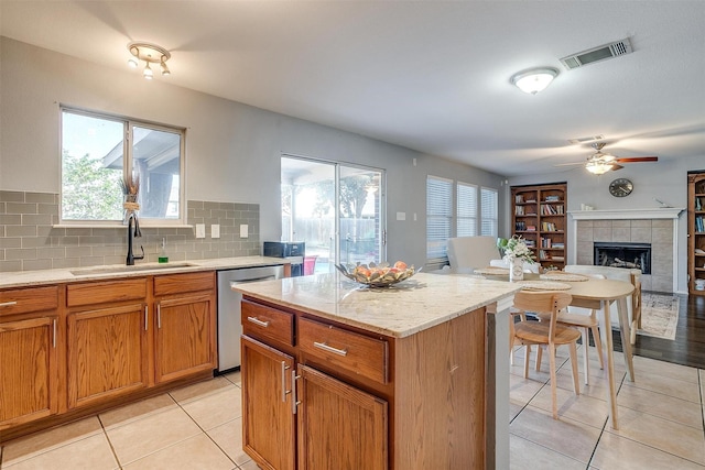 kitchen featuring visible vents, a tile fireplace, a sink, dishwasher, and a healthy amount of sunlight