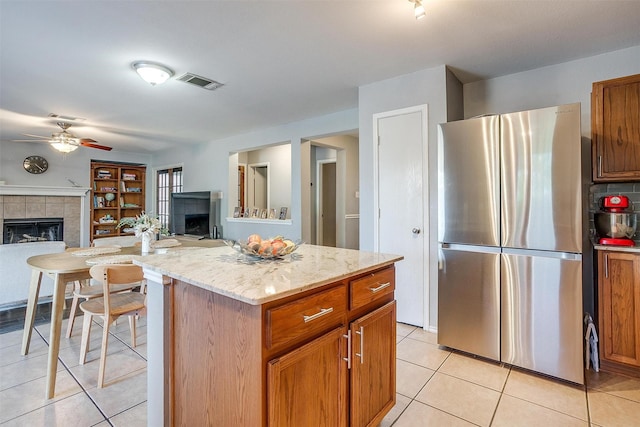 kitchen with visible vents, open floor plan, a tile fireplace, freestanding refrigerator, and light tile patterned flooring