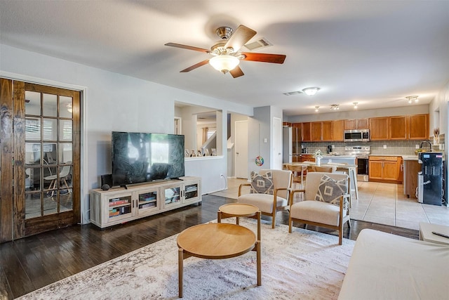 living room featuring visible vents, stairs, light wood-type flooring, and ceiling fan