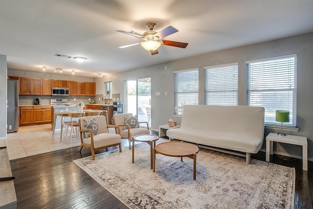 living room featuring visible vents, light wood-style flooring, and a ceiling fan