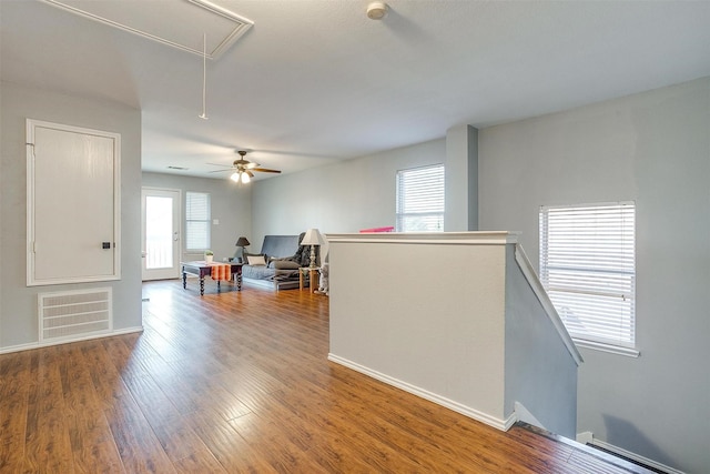 empty room with visible vents, baseboards, attic access, and wood finished floors