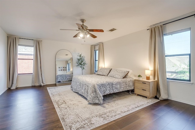 bedroom featuring dark wood-style floors, visible vents, baseboards, and a ceiling fan