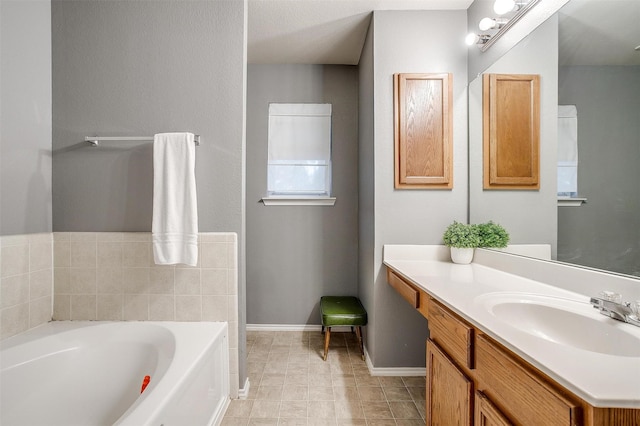 full bathroom with vanity, a garden tub, and baseboards