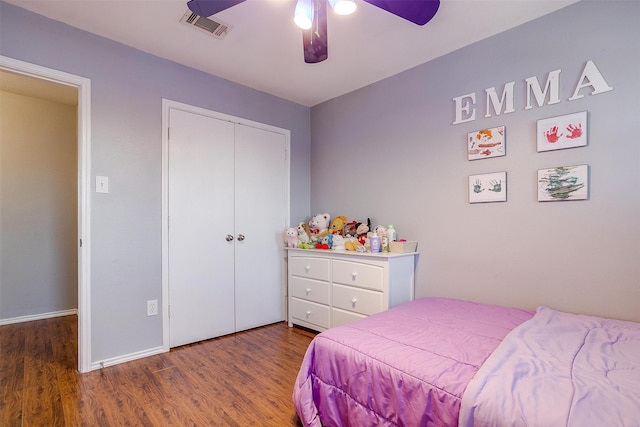 bedroom featuring visible vents, baseboards, wood finished floors, a closet, and a ceiling fan