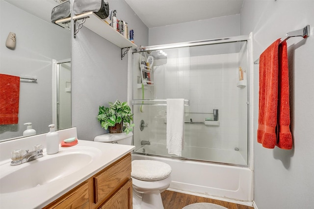 full bathroom featuring shower / bath combination with glass door, toilet, wood finished floors, and vanity