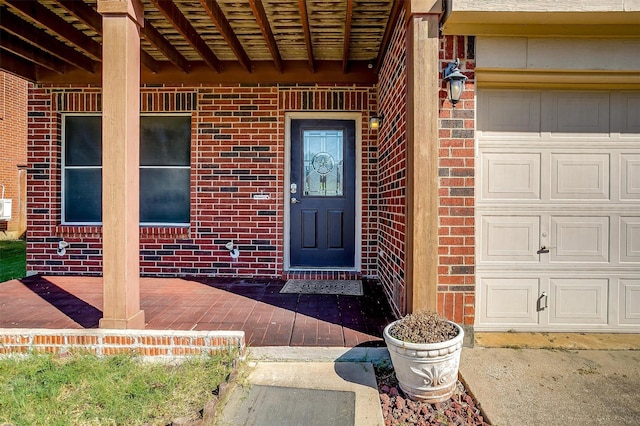 entrance to property featuring an attached garage and brick siding