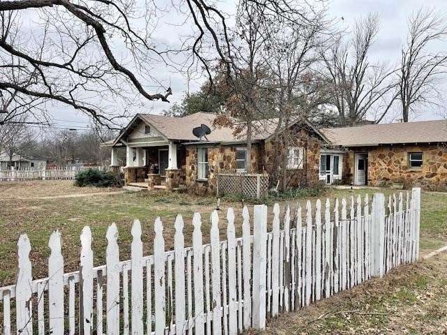 view of front of house featuring stone siding and a fenced front yard