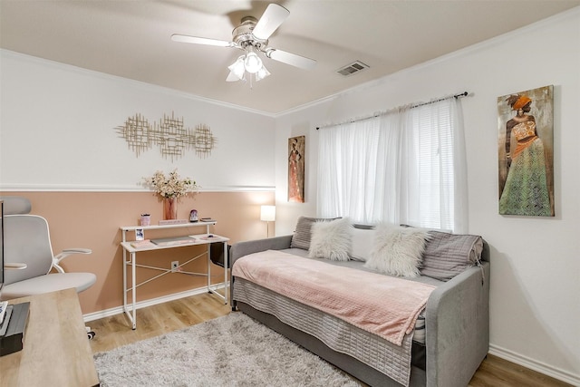 sitting room with ornamental molding, visible vents, and wood finished floors