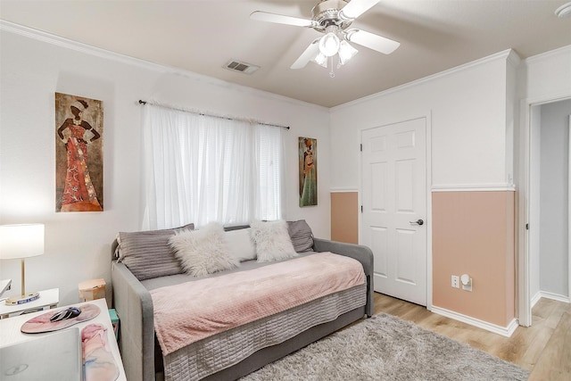 bedroom with ornamental molding, visible vents, light wood-style flooring, and a ceiling fan