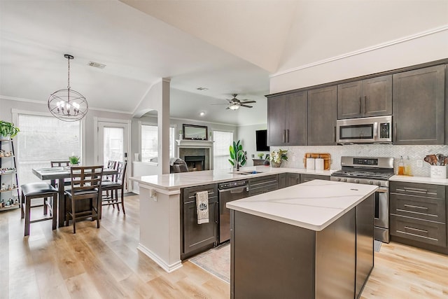 kitchen featuring dark brown cabinetry, visible vents, appliances with stainless steel finishes, a peninsula, and pendant lighting