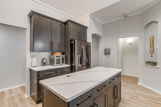 kitchen with light wood-style floors, stainless steel refrigerator with ice dispenser, light stone countertops, and decorative backsplash