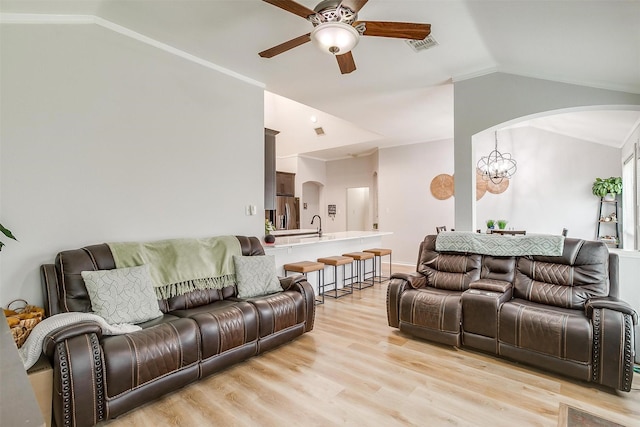 living room featuring lofted ceiling, arched walkways, light wood-style flooring, ceiling fan with notable chandelier, and visible vents