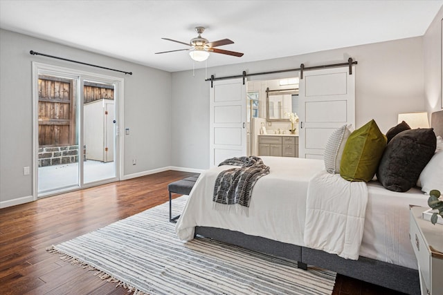 bedroom with a barn door, baseboards, connected bathroom, ceiling fan, and wood finished floors