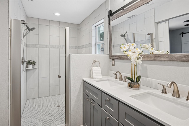 bathroom featuring double vanity, a stall shower, visible vents, and a sink