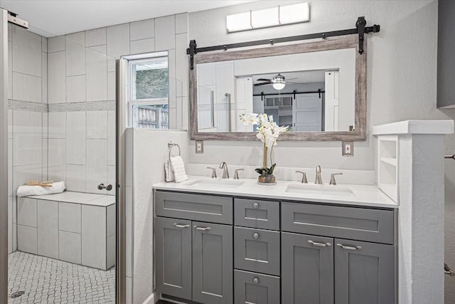 full bath featuring a textured wall, double vanity, a stall shower, and a sink