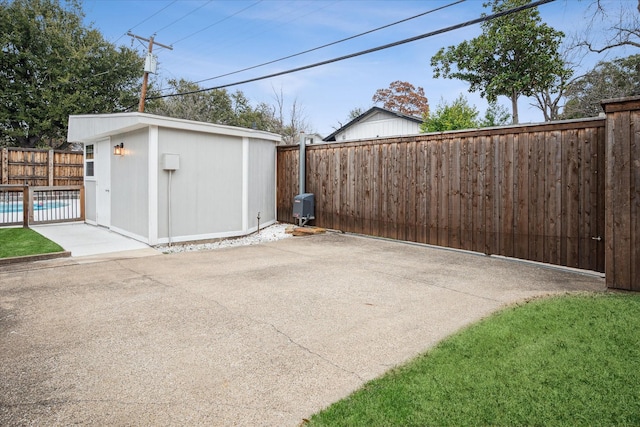 exterior space featuring a pool, a fenced backyard, an outdoor structure, and a storage shed