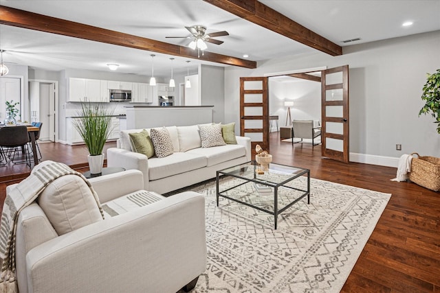 living room with dark wood-style flooring, visible vents, beamed ceiling, and baseboards