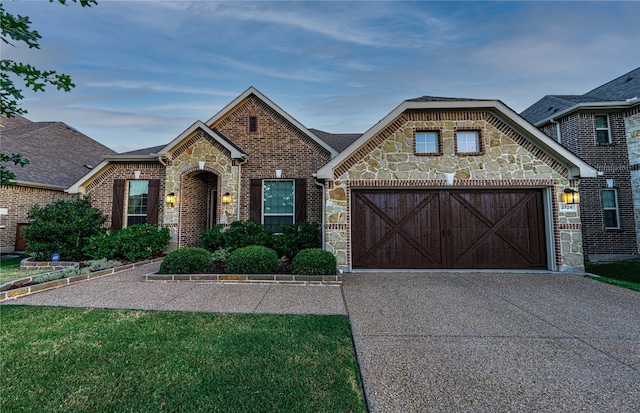 view of front of home with concrete driveway, brick siding, an attached garage, and stone siding