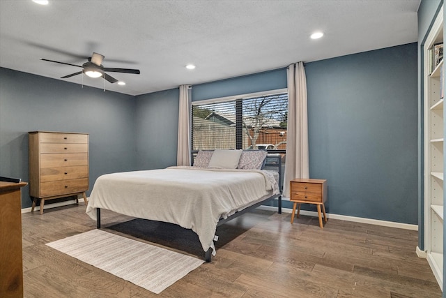 bedroom with a textured ceiling, dark wood finished floors, a ceiling fan, and baseboards