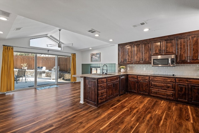 kitchen featuring stainless steel appliances, a peninsula, a sink, visible vents, and decorative backsplash