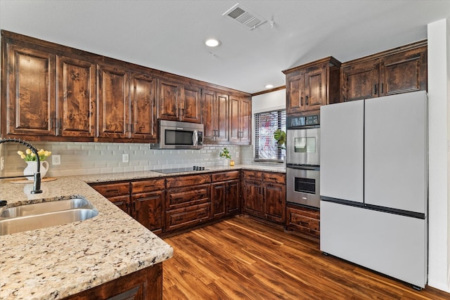 kitchen with visible vents, appliances with stainless steel finishes, light stone counters, dark wood-style flooring, and a sink