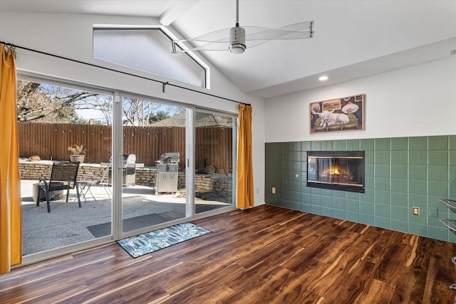 unfurnished living room with ceiling fan, a fireplace, vaulted ceiling, and wood finished floors