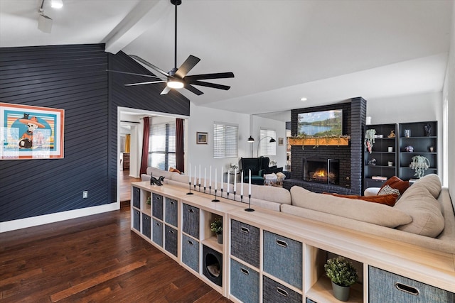 living room with a fireplace, lofted ceiling with beams, dark wood-type flooring, wood walls, and baseboards