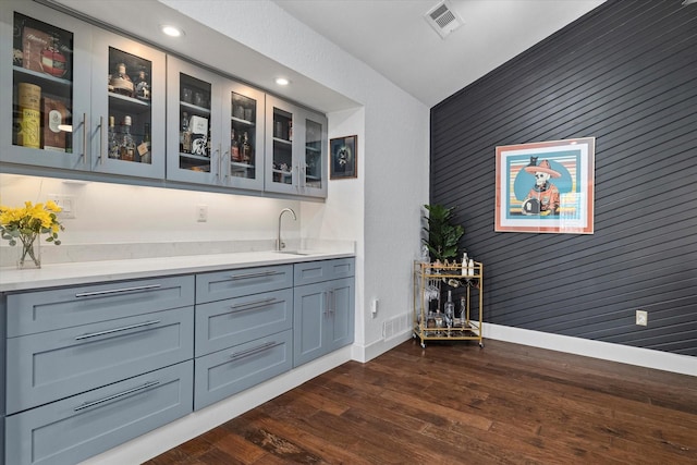 bar with dark wood-style flooring, indoor wet bar, visible vents, and baseboards