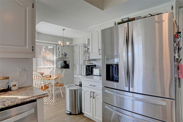 kitchen featuring light wood-type flooring, a notable chandelier, stainless steel appliances, white cabinets, and light countertops