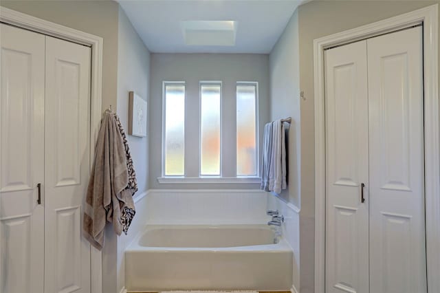 bathroom with a closet and a bath