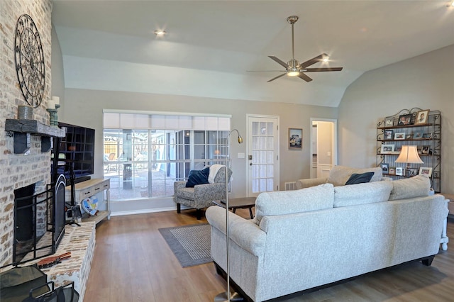 living area featuring ceiling fan, lofted ceiling, wood finished floors, and a fireplace