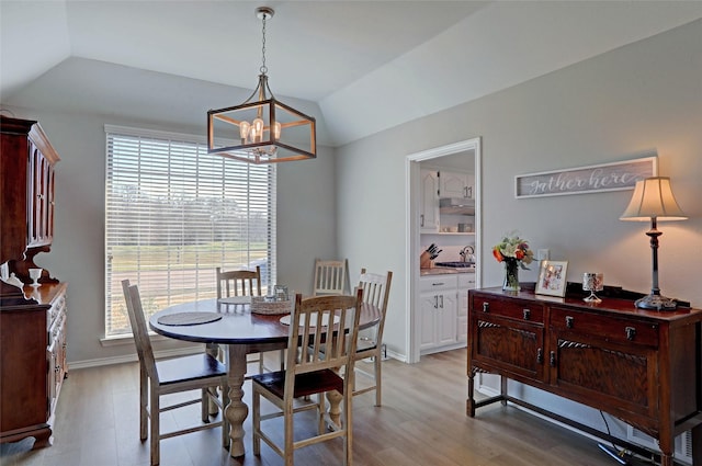 dining room with vaulted ceiling, baseboards, light wood-type flooring, and a chandelier