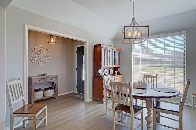 dining space with baseboards, a notable chandelier, a healthy amount of sunlight, and light wood finished floors