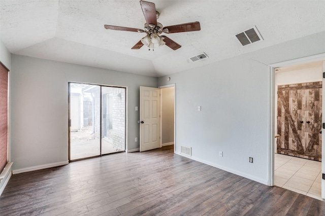 spare room featuring lofted ceiling, visible vents, and wood finished floors