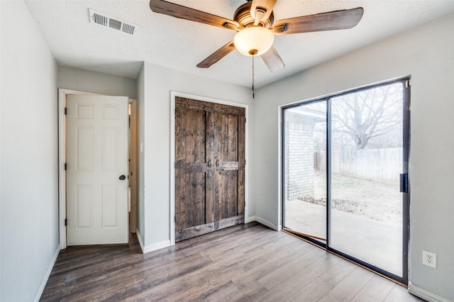 unfurnished bedroom featuring baseboards, visible vents, wood finished floors, access to outside, and a closet