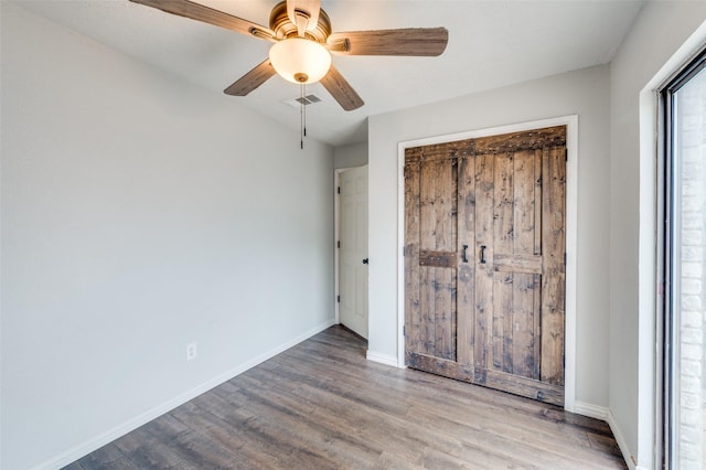 unfurnished bedroom with a closet, visible vents, baseboards, and wood finished floors