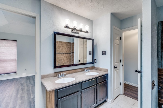 bathroom featuring a textured ceiling, double vanity, wood finished floors, and a sink