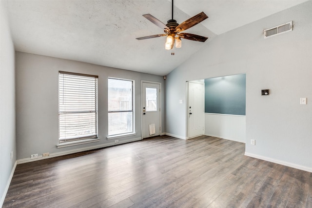 empty room featuring a ceiling fan, lofted ceiling, visible vents, and wood finished floors