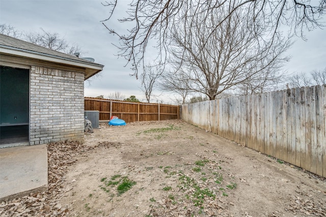 view of yard with central air condition unit and a fenced backyard