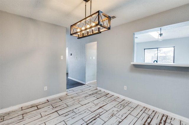 empty room with an inviting chandelier, visible vents, baseboards, and wood finished floors